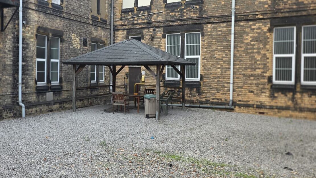 Outdoor courtyard at Beverley Road Masonic Hall, with a gravelled seating area and a covered gazebo beside the historic building.
