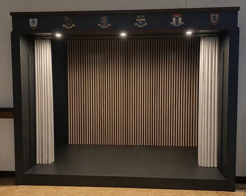 Indoor performance stage at Beverley Road Masonic Hall, featuring a raised platform and dark stage curtains.