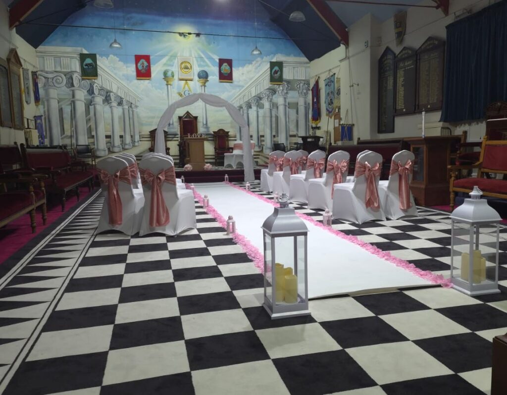Large Lodge Room at Beverley Road Masonic Hall in Hull, decorated with white chair covers and pink sashes for a wedding ceremony.