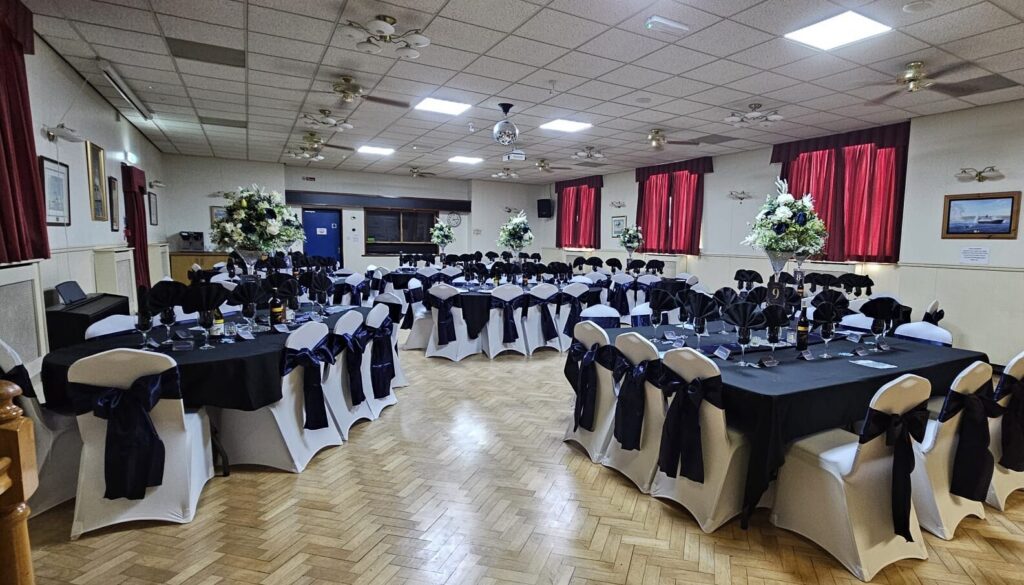 Dining Hall at Beverley Road Masonic Hall arranged with round tables, navy tablecloths and decorated chairs for a formal event.
